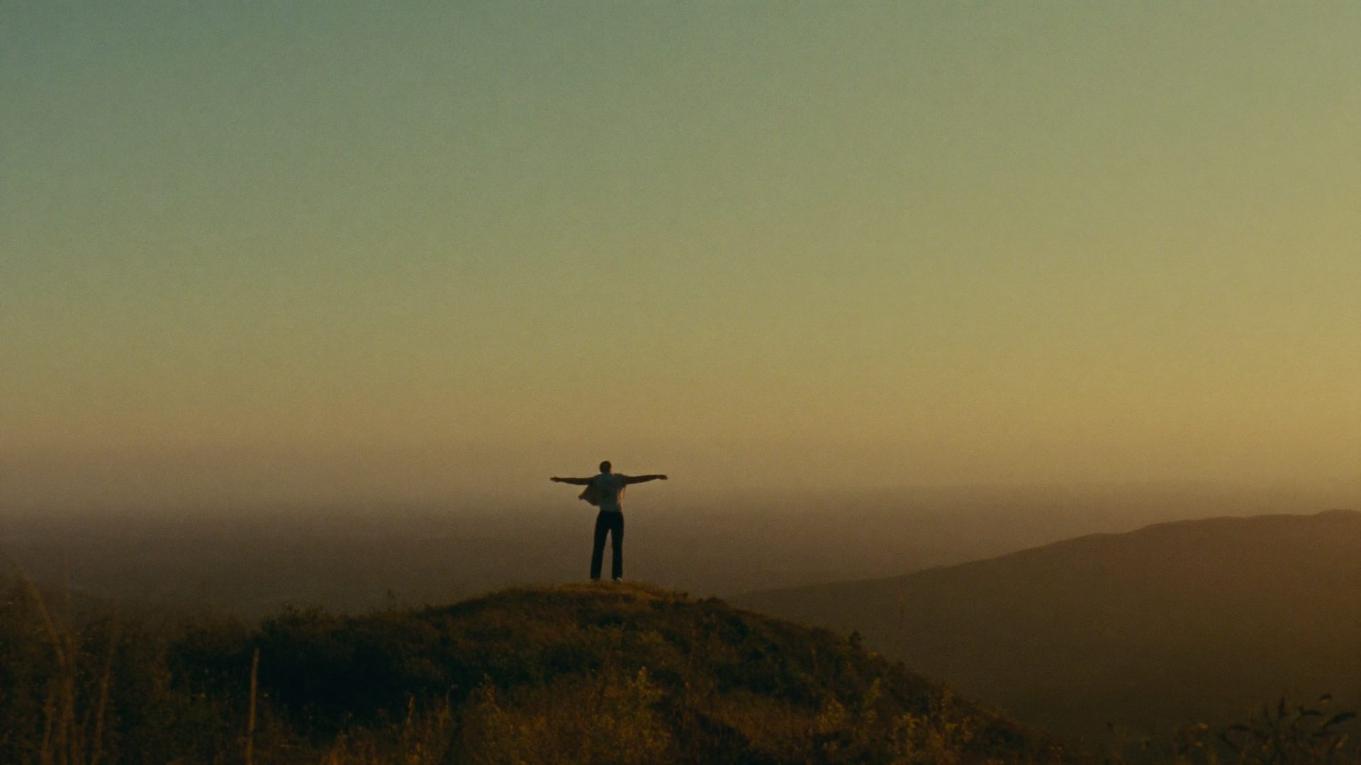A person on a hilltop at sunrise with arms open — freedom regained